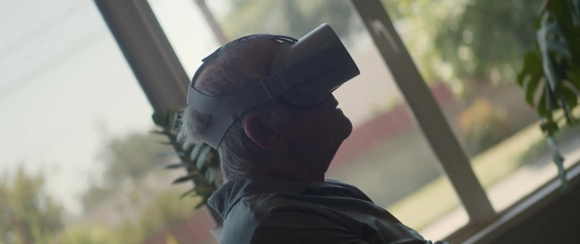 Man sitting near window laughs while experiencing input from VR goggles