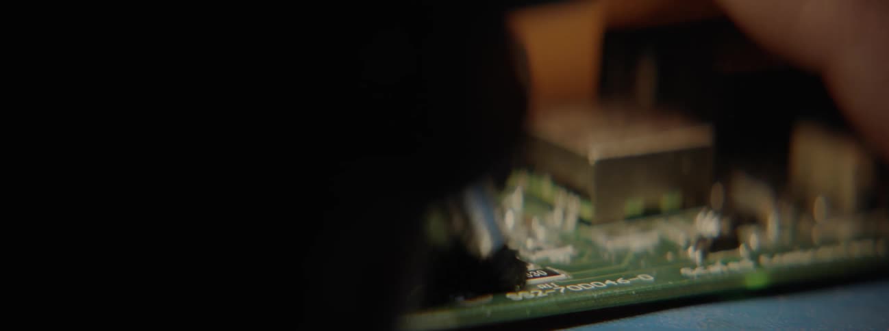 A person running a brush across a circuit board