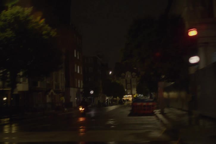 Motorcyclist waits on wet street at downtown intersection