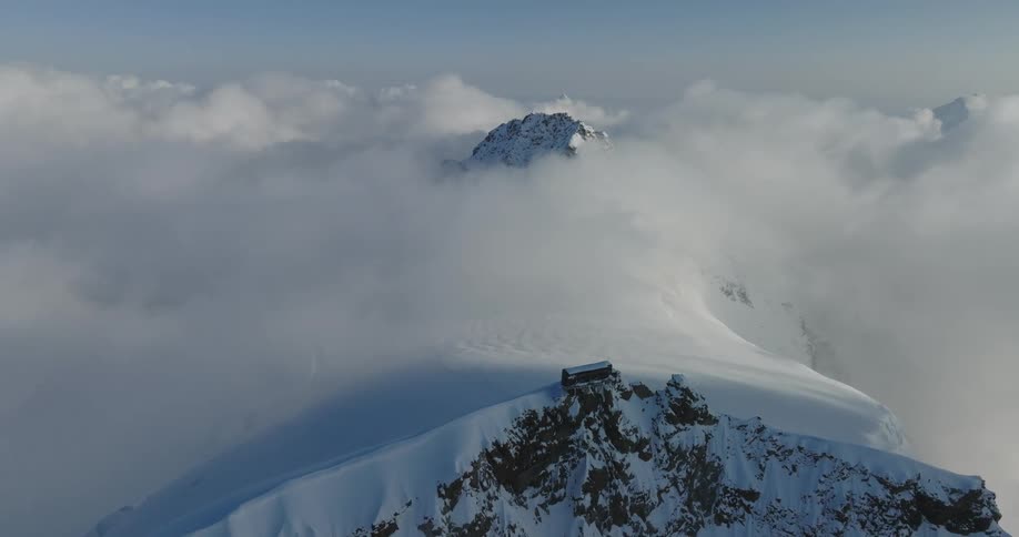 An aerial view of a snowcapped mountain peak above the clouds