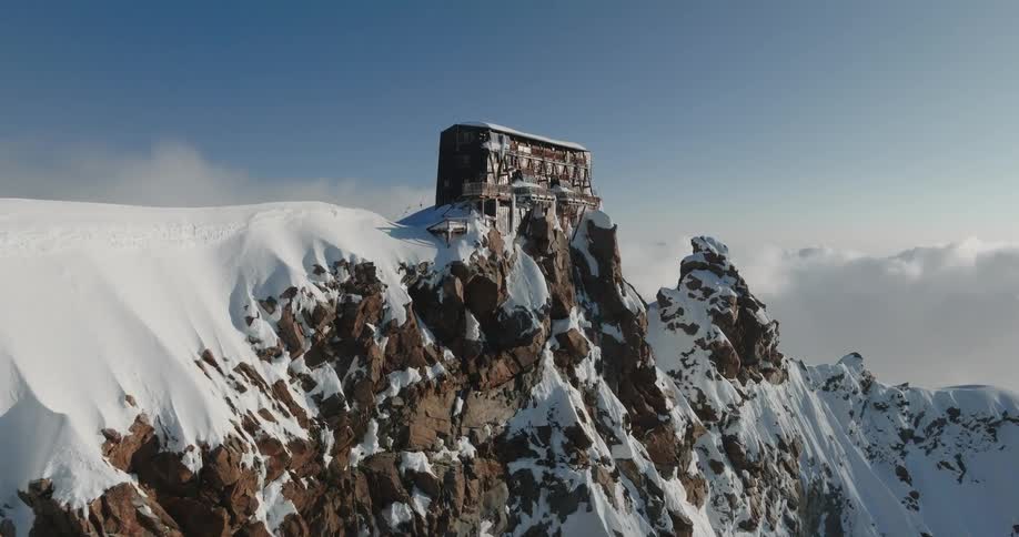 Aerial view of a building at the top of a snowy mountain peak