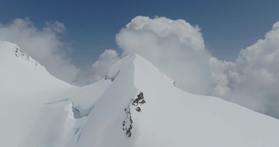 A think layer of snow completely covers a mountain range that is surrounded by clouds