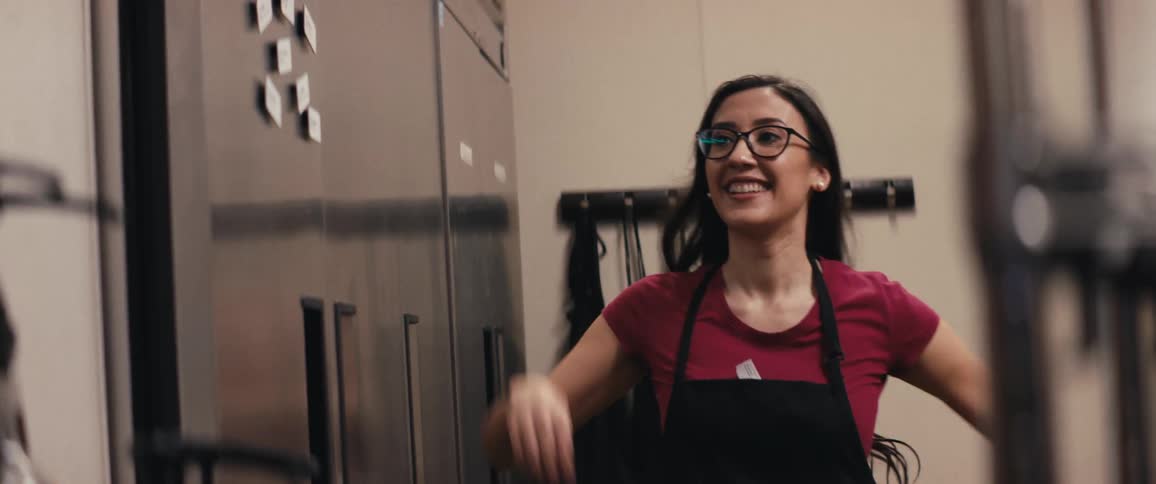 Female worker arrives at restaurant and puts on apron and name tag