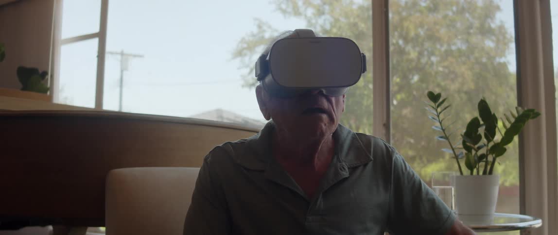 Elderly person sitting in an indoor environment using virtual reality glasses