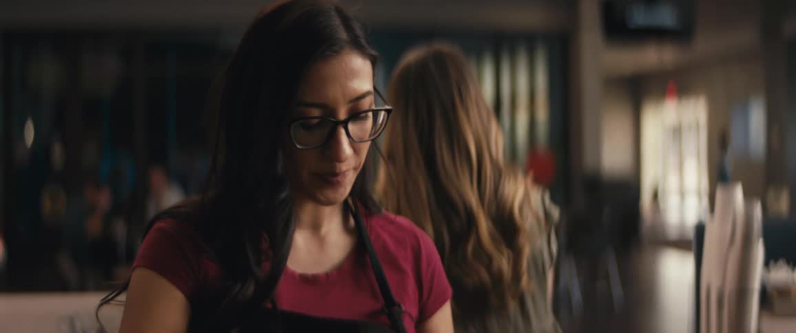 A woman in a coffee shop wearing glasses laughing and enjoying herself