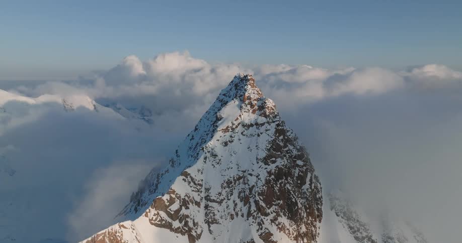 The mountain peak all covered in snow with a cloudy environment
