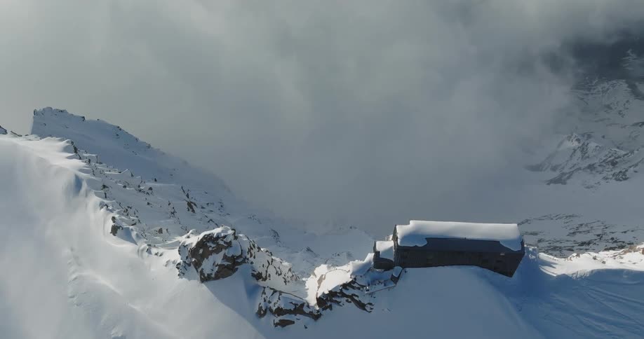 Aerial view of mountains at a higher level than the clouds and covered in snow