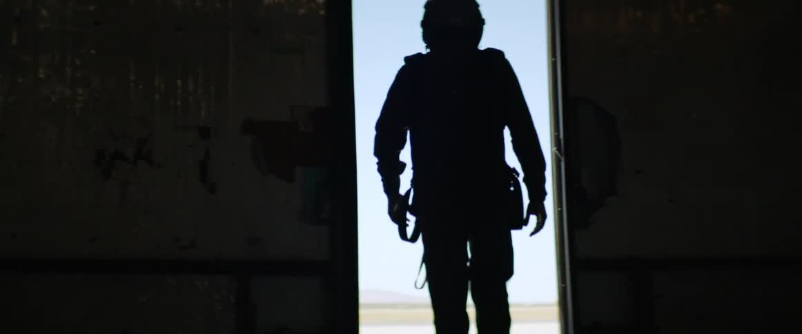 A man in a jumpsuit walks out of the hangar