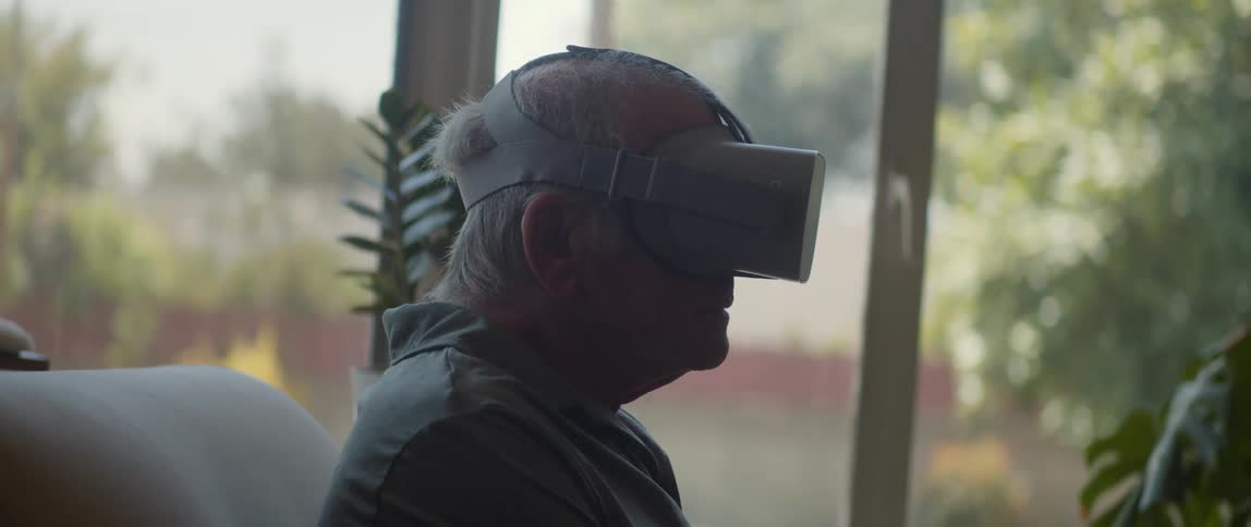 Older man sits at home near window using vr headset