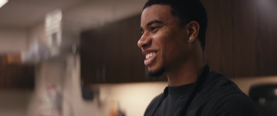 Black man talking and smiling in a lit room at night