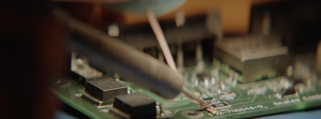 Person solders onto small green circuit board
