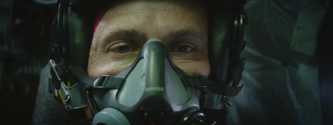 Close up of the face of a fighter pilot wearing a helmet and oxygen mask