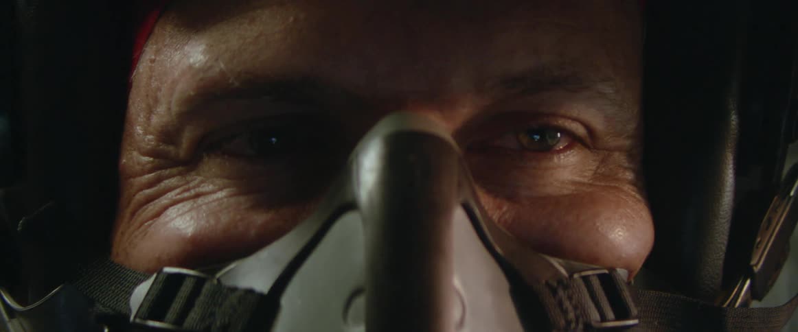 Close up of the face of a fighter pilot wearing a helmet and oxygen mask