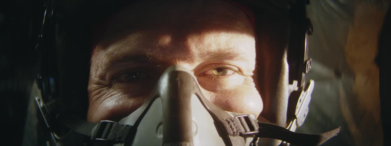 An airplane pilot smiles as sunlight flashes on his face