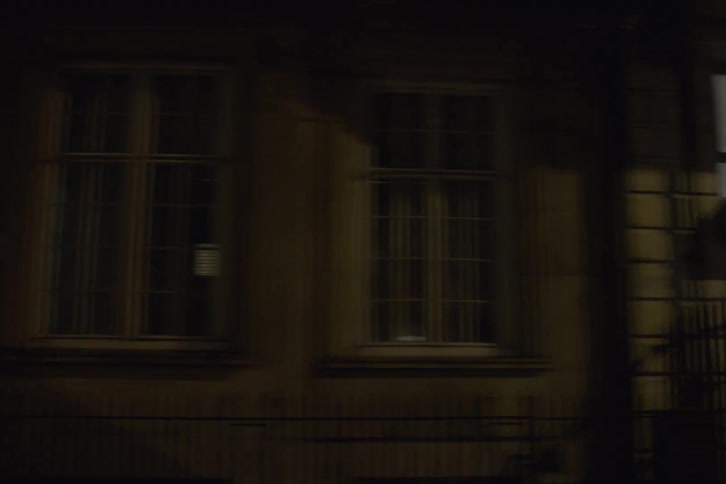 Cars occupy street near row of brownstones at night