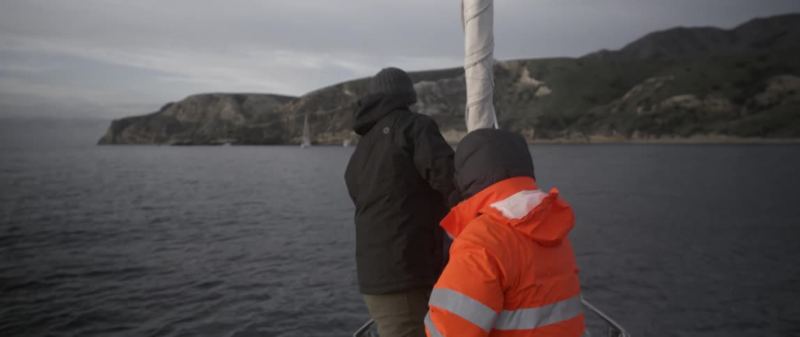 Two men work on the edge of a boat