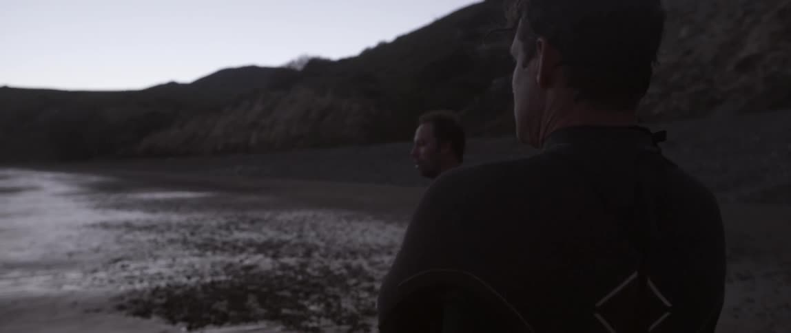 Two men stand on the beach on a cloudy day