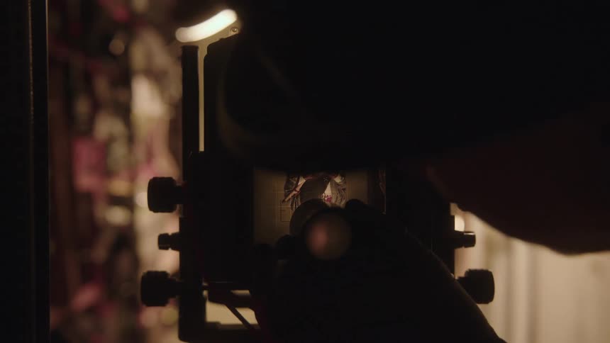 A vintage camera and a zoom magnifying glass being placed to observe the details of the cameras screen