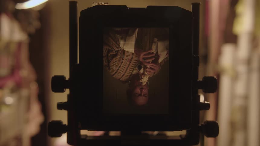 An indigenous man playing a musical instrument inside a device with an old screen