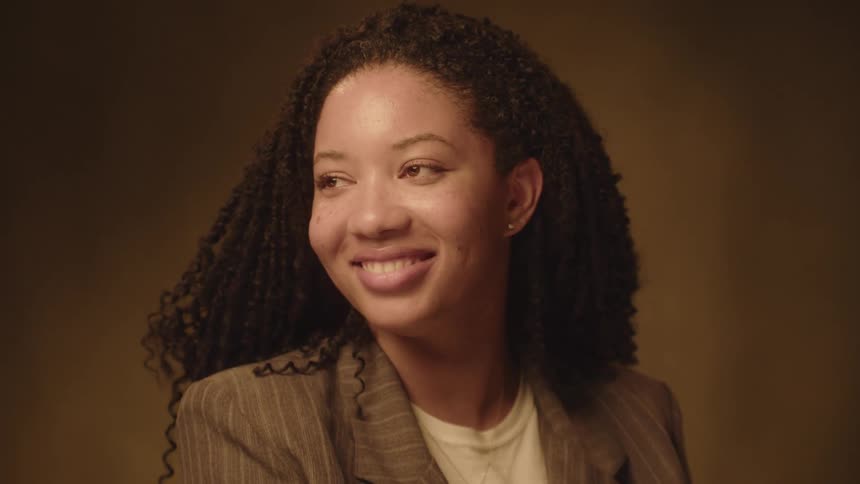 A black woman in formal wear posing for the camera and smiling