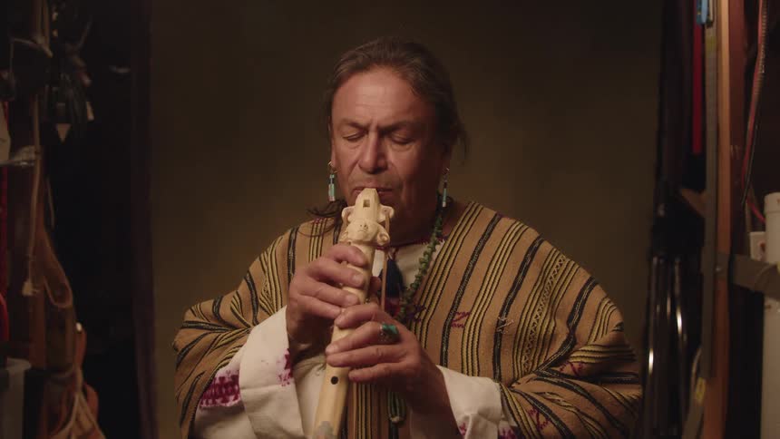 Man sits playing traditional flute