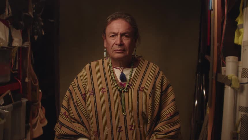 A man with his eyes closed is being photographed inside a room