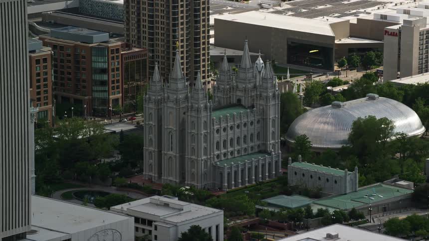 Aerial footage of Salt Lake City Utah showcasing the Salt Lake Temple and Mormon Tabernacle in downtown with partly cloudy skies and a religious ambiance