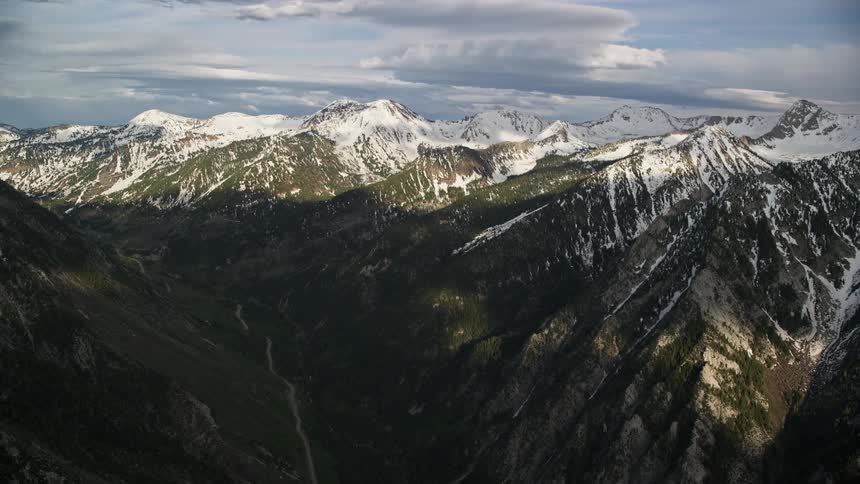 Aerial footage of the snow-capped peaks of the Wasatch Range in Utah during a partly cloudy day in winter