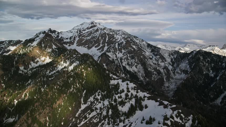 an aerial view of snow-capped peaks in Utah's Wasatch Range during a sunny day in summer