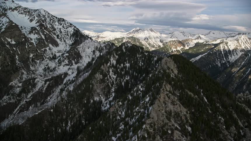 Aerial footage of snow-capped peaks and ridges in the Wasatch Range Utah during the day showcasing the natural beauty of the mountains