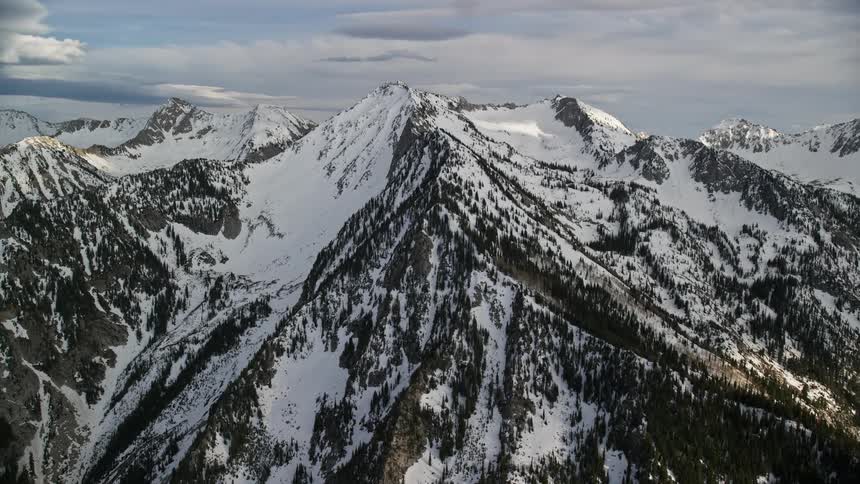 an aerial view of snow-covered ridges and peaks in the Wasatch Range Utah with partly cloudy skies and a winter landscape in the Southwest United States