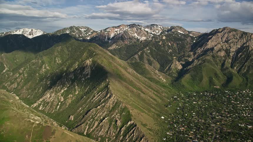 Fly over the beautiful Wasatch Range in Utah during the sunny summer capturing the breathtaking snow-capped peaks and showcasing the natural splendor of the Southwest United States