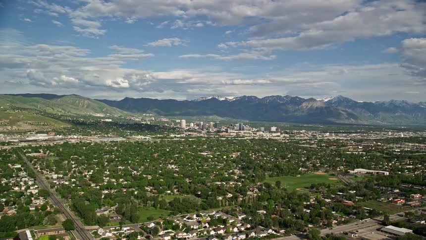 Aerial footage of flying over suburbs and approaching Downtown Salt Lake City Utah during a sunny day in summer