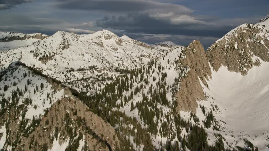 Aerial view of snow-covered Lone Peak in the snowy Wasatch Range Utah with partly cloudy skies