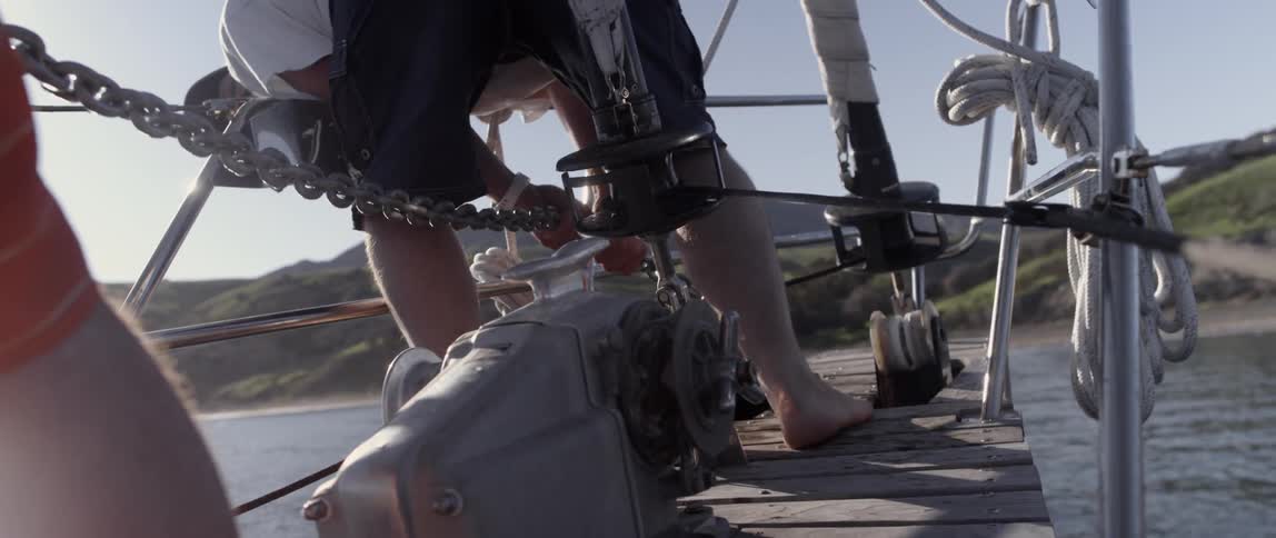 A man is holding onto a chain on a boat