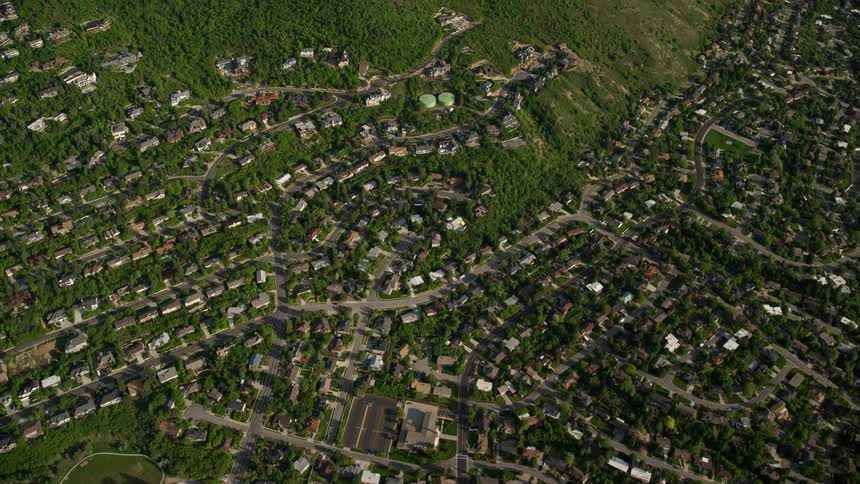A stunning aerial view of suburban homes with the green slopes of the Wasatch Range in the background capturing the beauty of Salt Lake City Utah during summertime