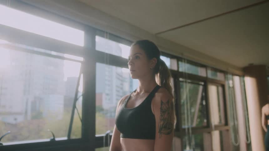 Woman lifting a dumbbell with both hands towards her chin in an indoor training environment