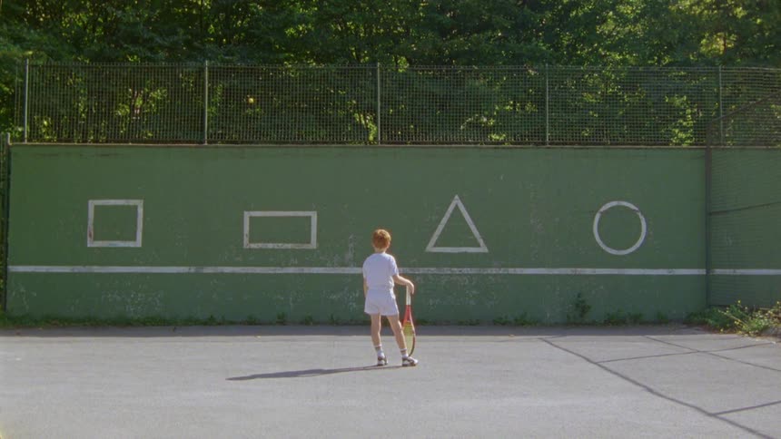 Boy holding a tennis racket and resting it on his foot