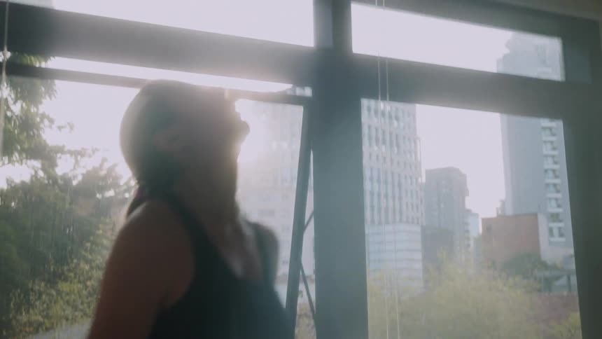 A young woman working out with a kettle bell inside on a sunny day