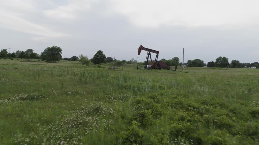 An oil pump works on a tree dotted prairie