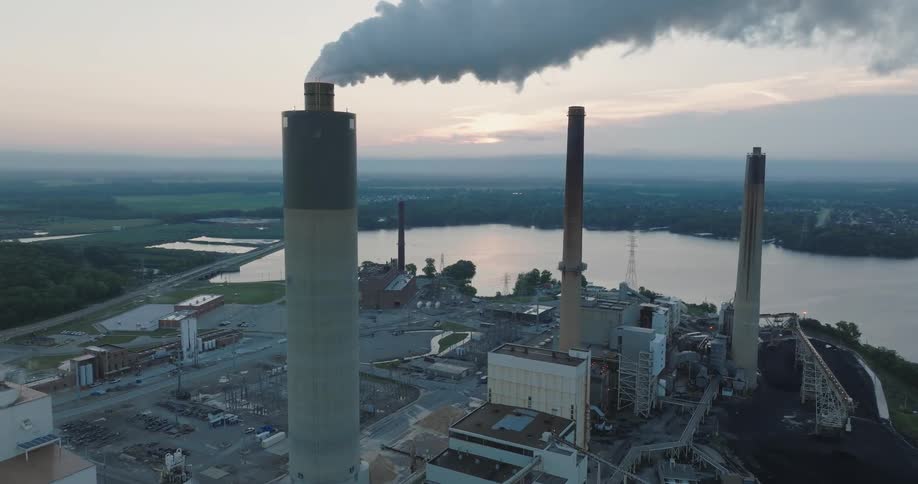 Tilt up reveal of smoke emanating from a tall stack at a coal fired power station