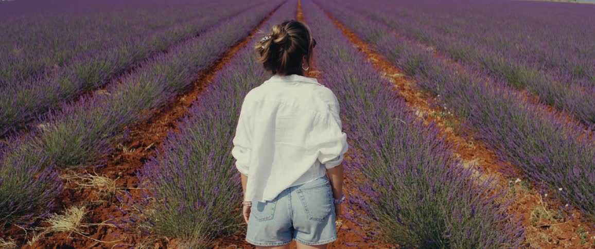 A woman standing and staring straight ahead in a field of plants
