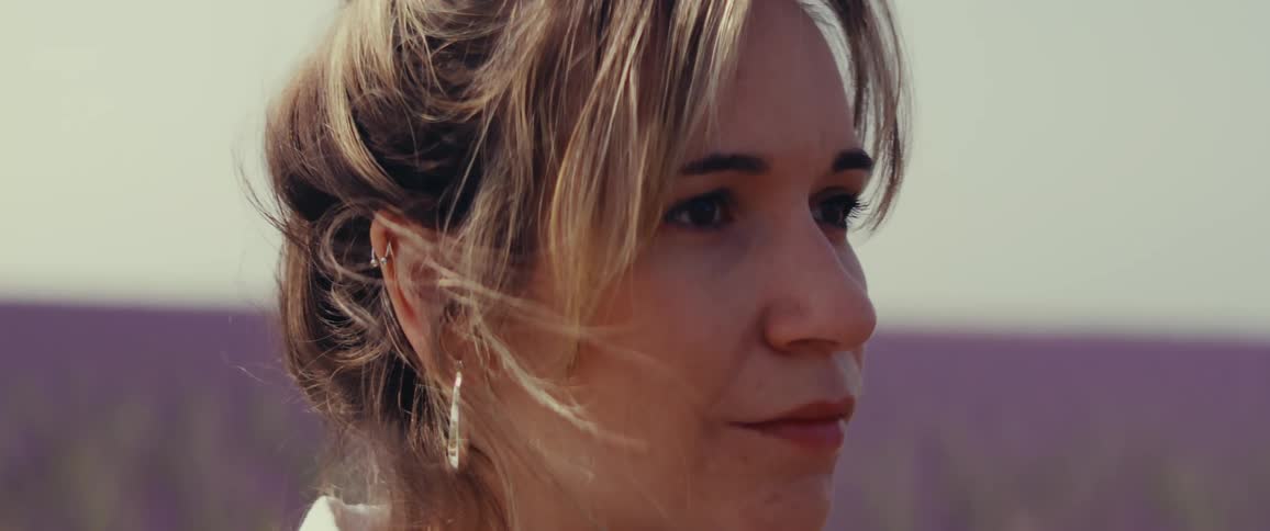 A woman smiles outside on a windy day