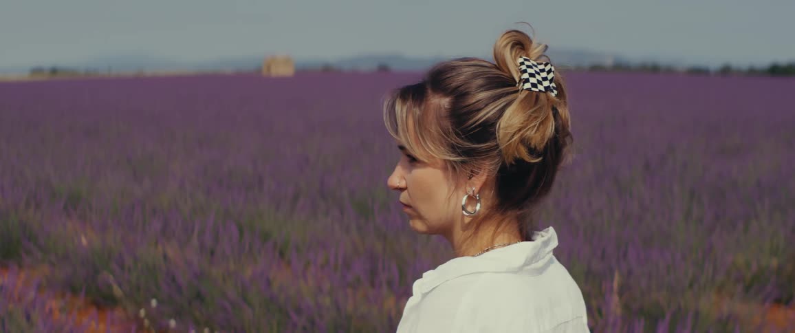 Woman standing alone in a grassland looking around at midday