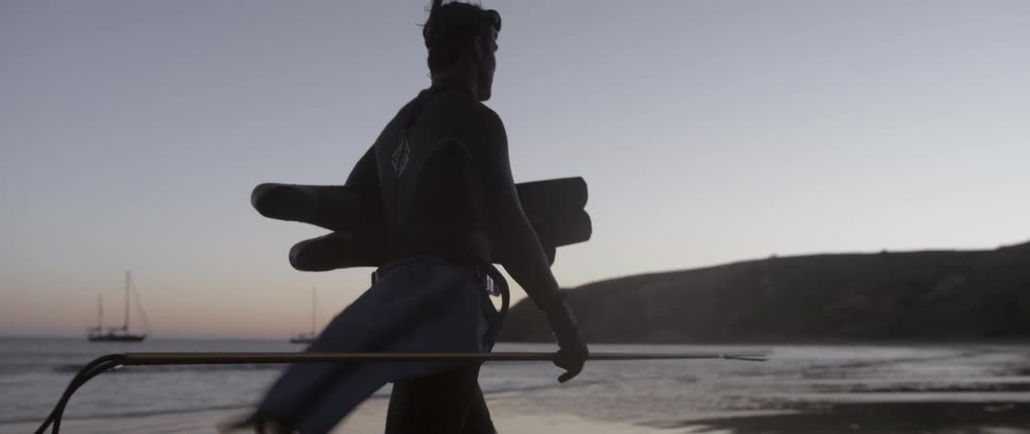 A man is walking carrying some items near the water