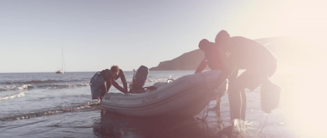 People drag a raft from the water onto the beach