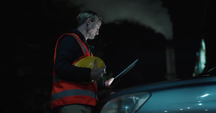 An engineer consults a tablet before putting on his hard hat