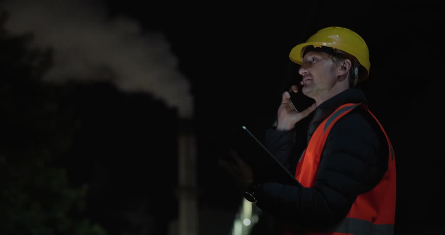 Man wearing a helmet and using a tablet while working at night