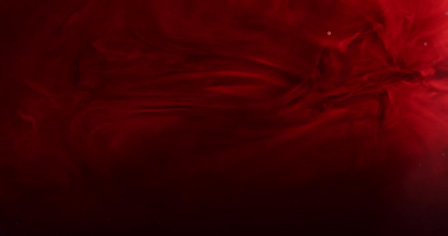 Wispy crimson layers expand and flow against dark background