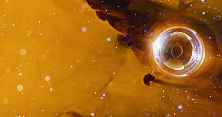 Bright sphere moving in yellow liquid with sparkling dots in an abstract manner